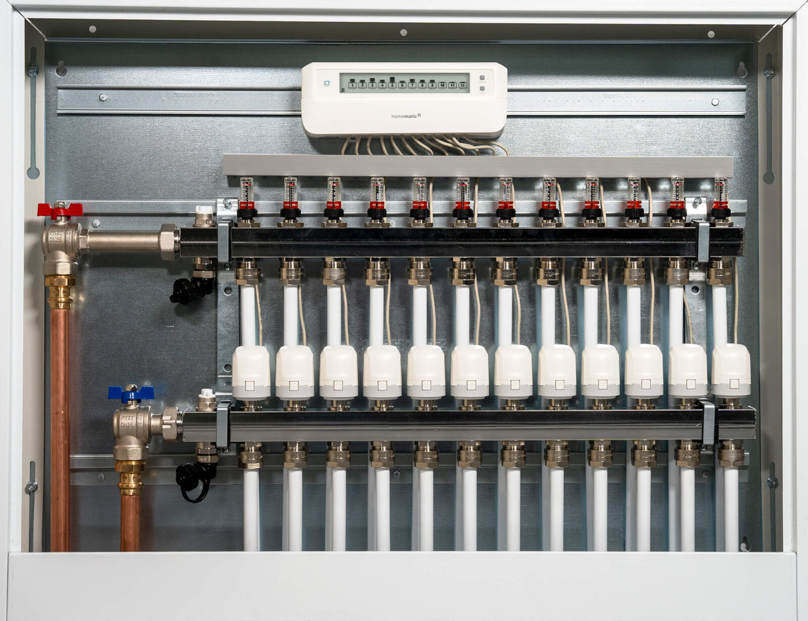 Perfekt abgestimmt: Der motorische Fußbodenheizungscontroller im Heizkreisverteiler (oben) koordiniert alle Stellantriebe und verteilt das Heizwasser präzise auf die einzelnen Heizkreise.